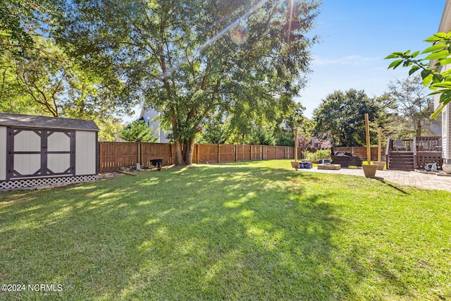 view of yard with a patio, a wooden deck, and a storage shed