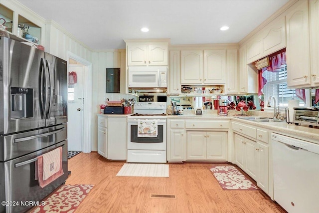 kitchen featuring cream cabinetry, sink, light wood-type flooring, and white appliances