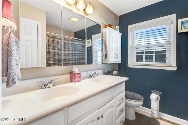 bathroom featuring vanity, a textured ceiling, toilet, and tile patterned floors