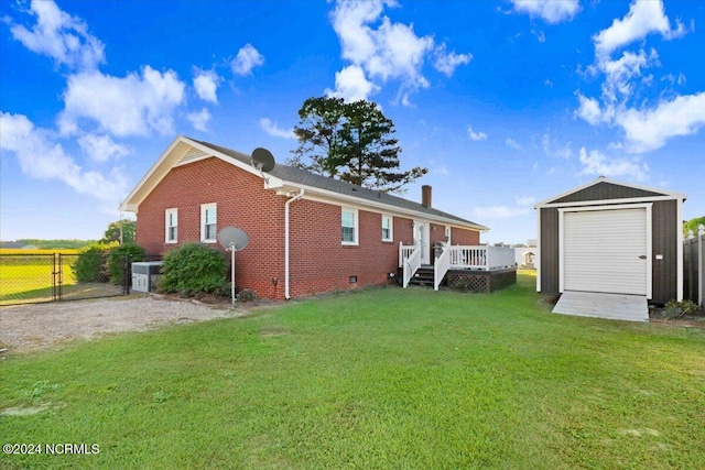 rear view of property featuring a yard, a deck, a garage, and an outdoor structure