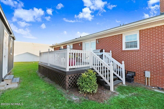 back of property featuring a deck and a lawn