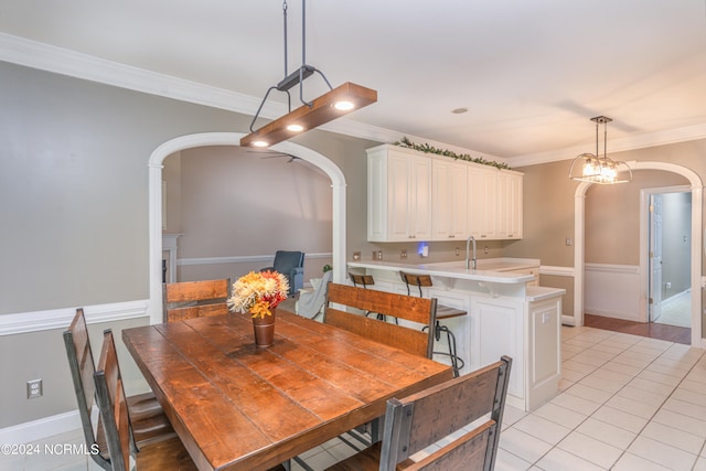 tiled dining space featuring crown molding, a chandelier, and sink