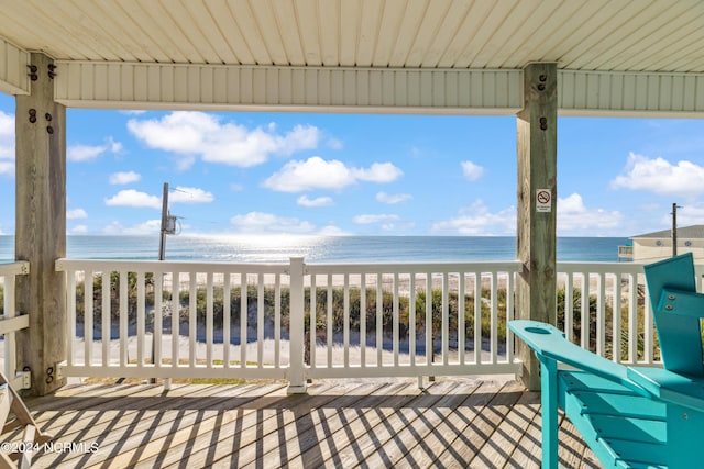 wooden deck with a water view and a beach view