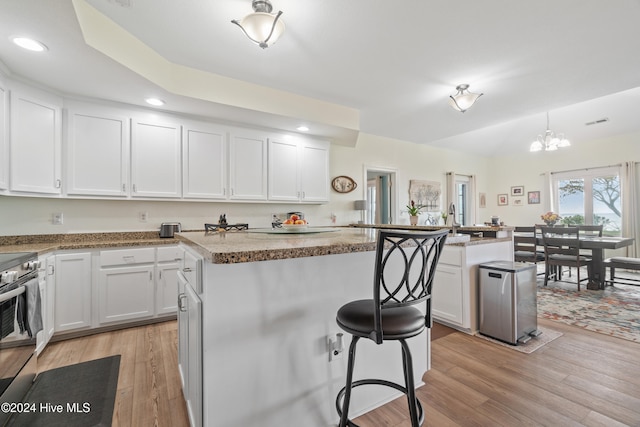 kitchen with white cabinetry, a center island, and light wood-type flooring