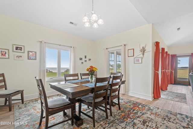 dining area with light hardwood / wood-style flooring, a notable chandelier, and lofted ceiling