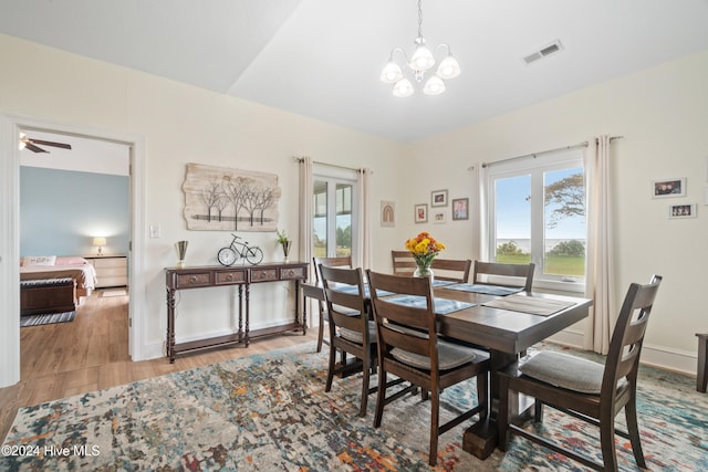 dining area featuring wood-type flooring and ceiling fan with notable chandelier