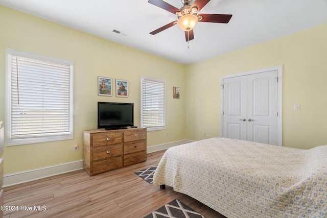 bedroom featuring light hardwood / wood-style flooring, multiple windows, a closet, and ceiling fan