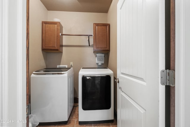 washroom with independent washer and dryer, light tile patterned flooring, a textured ceiling, and cabinets