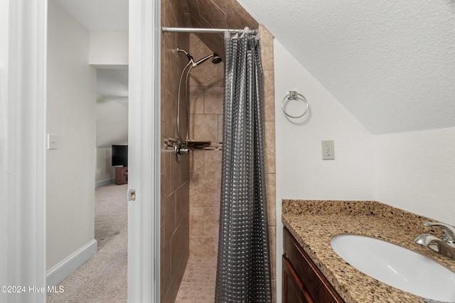 bathroom featuring vanity, a textured ceiling, walk in shower, and vaulted ceiling