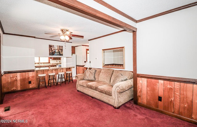 living room with wooden walls, dark colored carpet, and ceiling fan