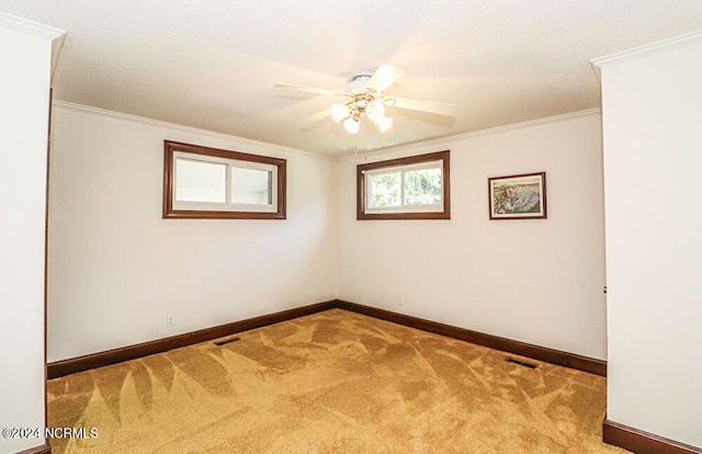 empty room featuring crown molding, carpet flooring, and ceiling fan