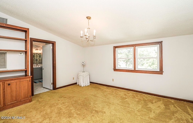 carpeted empty room featuring a chandelier and vaulted ceiling