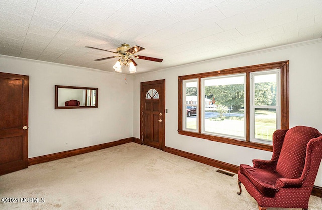 sitting room with crown molding, light colored carpet, and ceiling fan