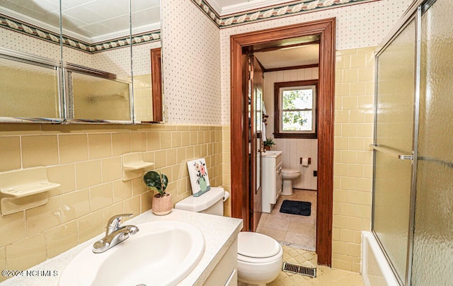 full bathroom with tile walls, vanity, enclosed tub / shower combo, and toilet