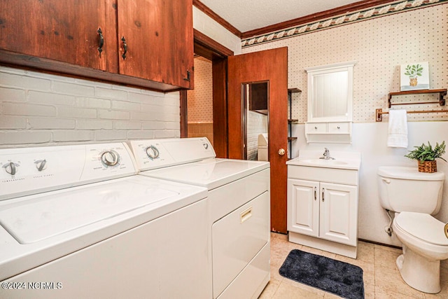 clothes washing area featuring light tile patterned floors, washer and dryer, a textured ceiling, crown molding, and sink