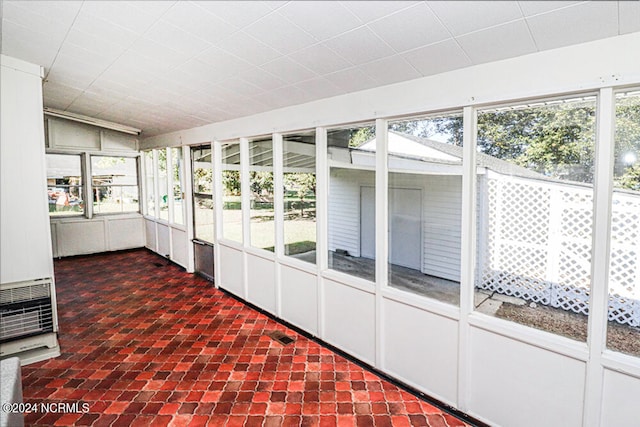 unfurnished sunroom featuring heating unit and plenty of natural light