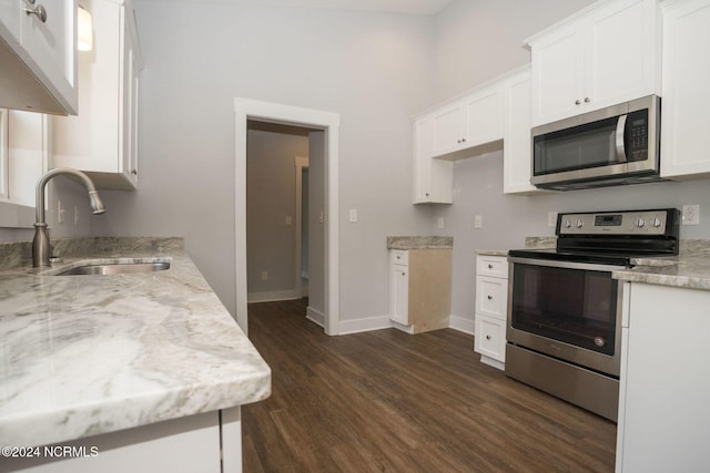 kitchen with light stone countertops, sink, dark hardwood / wood-style flooring, white cabinetry, and stainless steel appliances