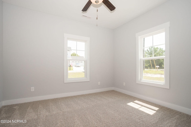 carpeted empty room with ceiling fan and plenty of natural light