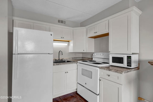 kitchen with a textured ceiling, white cabinetry, dark tile patterned floors, sink, and white appliances