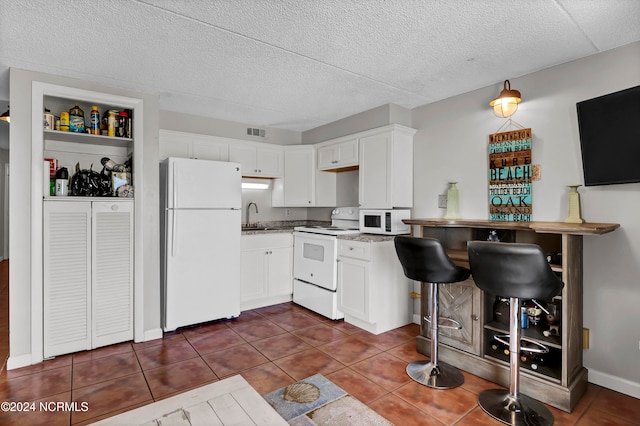 kitchen with white appliances, sink, a textured ceiling, dark tile patterned floors, and white cabinets