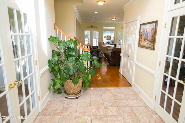 hall with ornamental molding, french doors, and light wood-type flooring