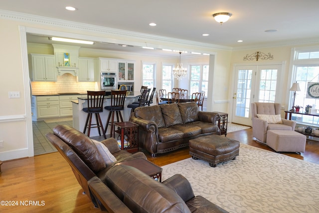 living room with ornamental molding, a chandelier, and light wood-type flooring