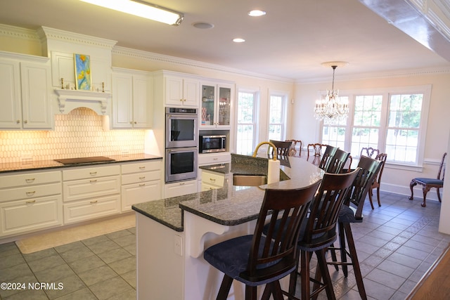 kitchen featuring an island with sink, hanging light fixtures, a wealth of natural light, sink, and white cabinets