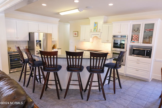 kitchen with wine cooler, a breakfast bar, white cabinetry, ornamental molding, and stainless steel appliances