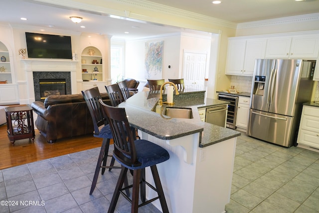 kitchen with appliances with stainless steel finishes, crown molding, white cabinetry, and built in features