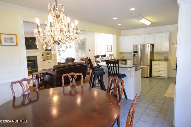 tiled dining area with a premium fireplace and ornamental molding