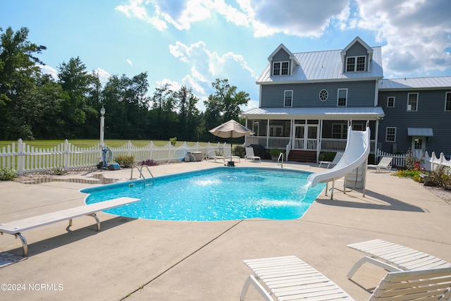 view of swimming pool featuring a water slide, a diving board, a patio area, and a sunroom