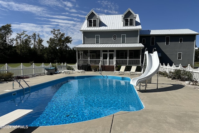 view of swimming pool with a patio area, a water slide, a diving board, and a sunroom