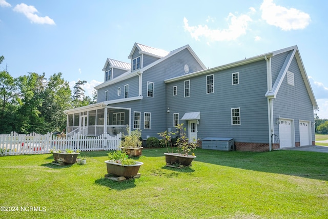 back of property with a sunroom, a lawn, and a garage