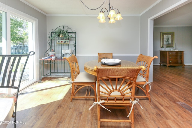 dining area with ornamental molding, hardwood / wood-style floors, and a notable chandelier