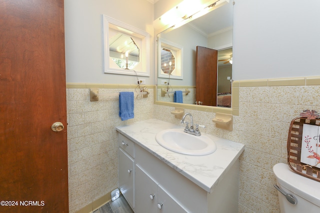 bathroom with vanity, toilet, and tile walls