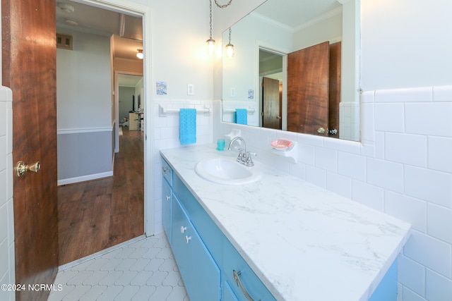 bathroom with tile walls, vanity, hardwood / wood-style floors, and ornamental molding