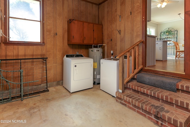 laundry area featuring wooden walls, electric water heater, crown molding, washer and dryer, and ceiling fan