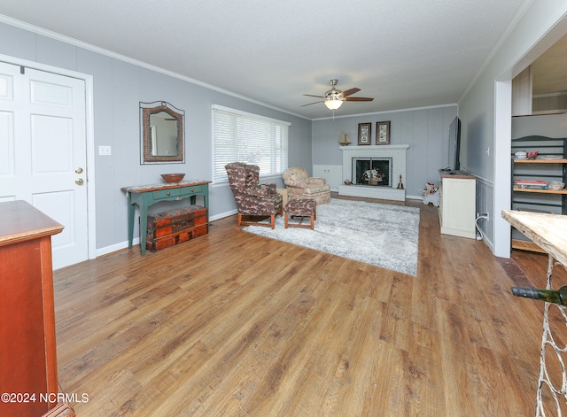 living room with hardwood / wood-style floors, a fireplace, crown molding, and ceiling fan