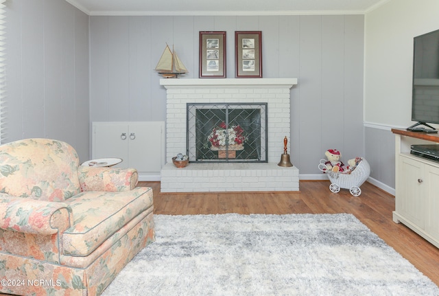 living room featuring light hardwood / wood-style floors, crown molding, and a fireplace