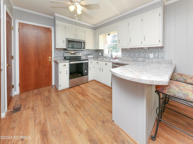 kitchen featuring appliances with stainless steel finishes, kitchen peninsula, light wood-type flooring, and white cabinets