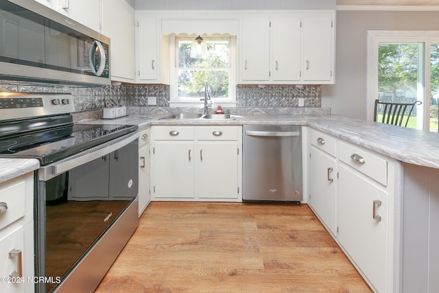 kitchen with sink, white cabinets, stainless steel appliances, and light wood-type flooring