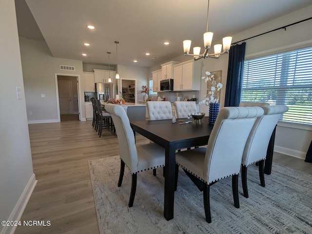 dining space with wood-type flooring and an inviting chandelier