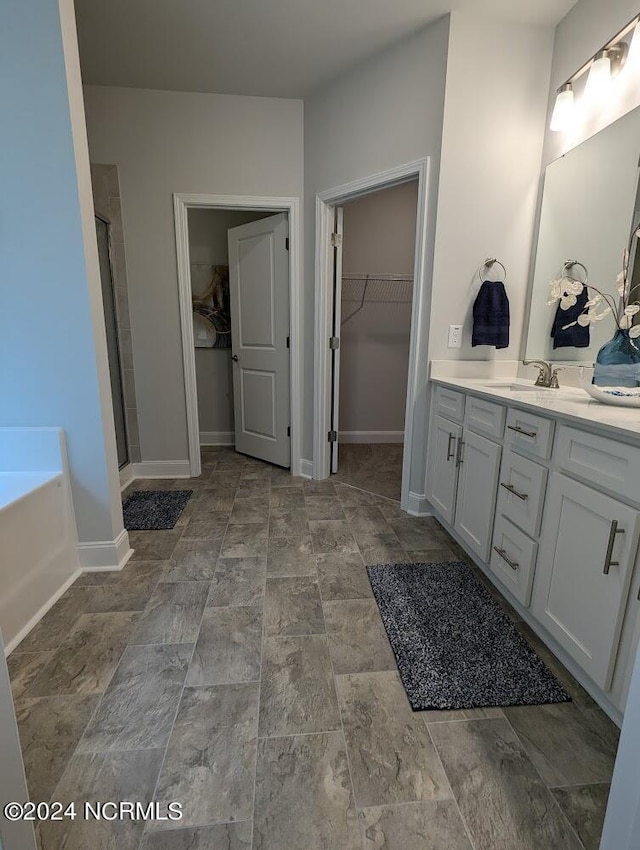 1491 Pecan Drive Model Home, Nashville, NC 27856 - bathroom featuring a spacious closet, stone finish floor, vanity, and a stall shower