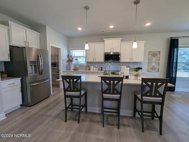 kitchen with white cabinets, hanging light fixtures, and stainless steel appliances