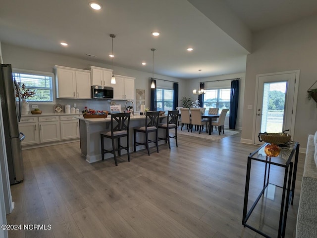 kitchen featuring a center island with sink, pendant lighting, stainless steel appliances, and a healthy amount of sunlight