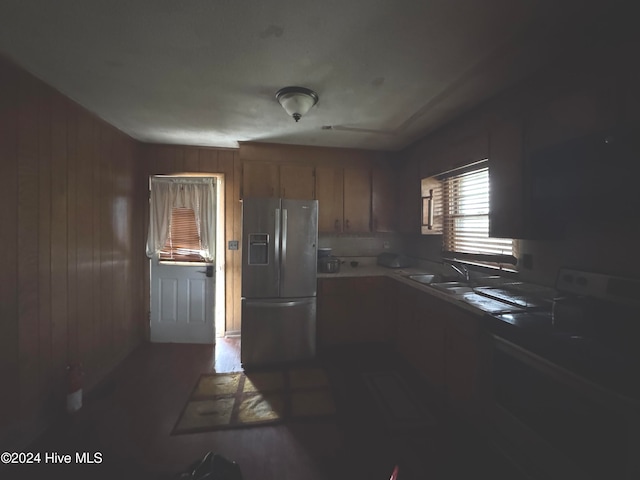 kitchen with refrigerator with ice dispenser, wooden walls, and sink