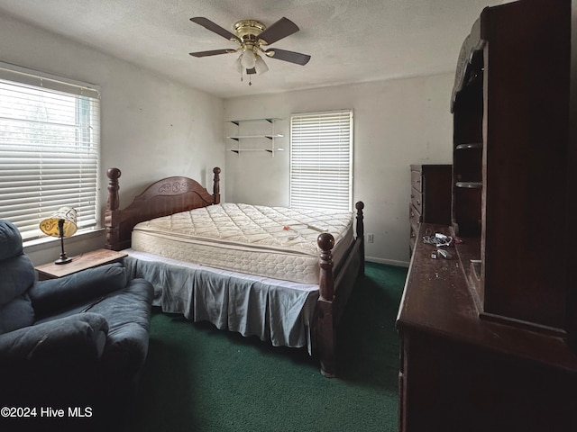 bedroom with ceiling fan, dark carpet, and a textured ceiling