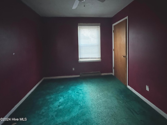 empty room featuring ceiling fan, dark carpet, and a baseboard radiator