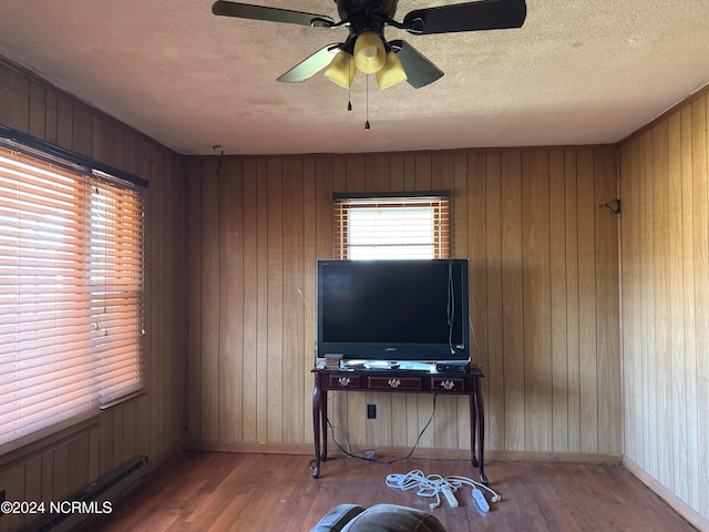 living room with hardwood / wood-style floors, ceiling fan, wood walls, and a textured ceiling