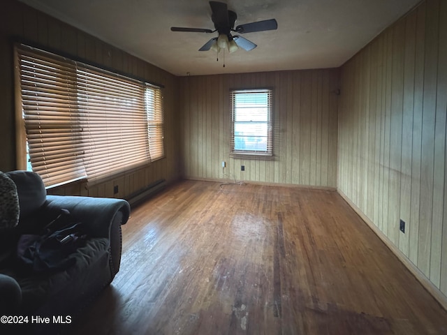 unfurnished room with hardwood / wood-style floors, ceiling fan, and wooden walls